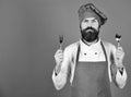 Chef holds cutlery. Cook with serious face in burgundy uniform Royalty Free Stock Photo