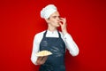 Chef holds a dish on a red isolated background and shows a sign of good taste, a kitchen worker in uniform cooked pasta Royalty Free Stock Photo