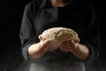 The chef holds the dough for bread, pizza, sweets. On a black background. Close-up,Food concept