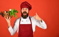 Chef holds lettuce, tomato, pepper and garlic. Man with beard