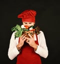 Chef holds lettuce, tomato, pepper and mushrooms. Healthy cooking concept. Cook with calm face in burgundy uniform