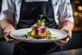 Chef holds a plate with a high gastronomic dish decorated with flowers
