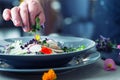 Chef in hotel or restaurant kitchen cooking, only hands. He is working on the micro herb decoration. Preparing vegetable salad