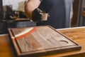 Chef in a hotel or restaurant kitchen prepearing food. Putting sauce in a saucepan on a rustic wooden cuttingboard.