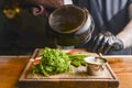 Chef in a hotel or restaurant kitchen prepearing food. Putting sauce in a saucepan on a rustic wooden cuttingboard.