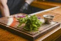 Chef in a hotel or restaurant kitchen prepearing food. Putting sauce in a saucepan on a rustic wooden cuttingboard.