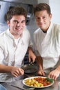 Portrait Of Chef Instructing Trainee In Restaurant Kitchen