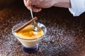 Chef introducing a spoon inside a glass of burnt cream