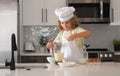 Chef kid boy baking on the kitchen. Child chef cook prepares food at kitchen. Kids cooking. Teen boy with apron and chef Royalty Free Stock Photo