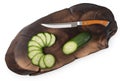 Chef knife on oak cutting board with slices of cucumber isolated on a white, top view, close up Royalty Free Stock Photo