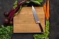 Chef Knife on Wooden Chopping Board with Fresh Vegetables Background. Vegetarian Raw Food. Royalty Free Stock Photo