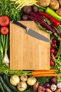 Chef Knife on Wooden Chopping Board with Fresh Vegetables Background. Vegetarian Raw Food. Royalty Free Stock Photo