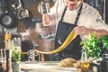 Chef making spaghetti noodles with pasta machine on kitchen table with some ingredients around Royalty Free Stock Photo