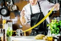 Chef making spaghetti noodles with pasta machine on kitchen table with some ingredients around Royalty Free Stock Photo