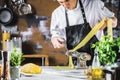 Chef making spaghetti noodles with pasta machine on kitchen table with some ingredients around