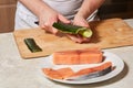 Chef making sushi rolls. Cutting cucumber and salmon fish Royalty Free Stock Photo