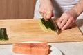 Chef making sushi rolls. Cutting cucumber and salmon fish Royalty Free Stock Photo