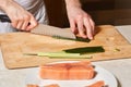 Chef making sushi rolls. Cutting cucumber and salmon fish Royalty Free Stock Photo