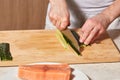 Chef making sushi rolls. Cutting cucumber and salmon fish Royalty Free Stock Photo