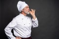 Chef making tasty delicious gesture by kissing fingers. Confident bearded male chef in white uniform with perfect sign.