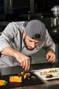 Chef man decorating cake at kitchen. Chef male making orange cake. Royalty Free Stock Photo