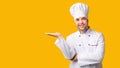 Chef Man Holding Invisible Object On Open Palm, Yellow Background