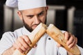 Chef man at kitchen restaurant. Closeup male professional breaking bread. Royalty Free Stock Photo