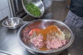The chef mixes minced pork with different ingredients.
