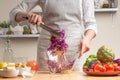 The chef mixes the salad, stir, in the process of a vegetarian salad in the home kitchen. Light background for restaurant menu