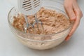 Chef mixing chocolate cake frosting in a glass bowl