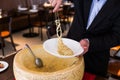 Chef neatly plating spaghetti carbonara in cheese wheel on white plate