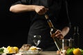 Chef opens Italian dry wine with oysters with lemon, on a dark background