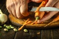 The chef peels fresh carrots on a wooden cutting board. Close-up of cook hands while preparing vegetarian food Royalty Free Stock Photo