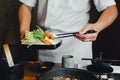 Chef pinching vegetables into hot pot by chopsticks before pouring soy soup