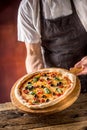 Chef and pizza. Chef offering pizza in hotel or restaurant Royalty Free Stock Photo