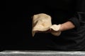 Chef pizza maker preparing pizza, holding rolled dough in hands. On a black background for design Royalty Free Stock Photo