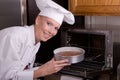 Chef places cake in oven Royalty Free Stock Photo