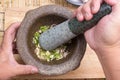 Chef pound coriander, pepper and garlic with pestle on mortar Royalty Free Stock Photo