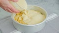 Chef pouring cake batter into a baking pan on the top of apple slices. Apple cake preparation process Royalty Free Stock Photo