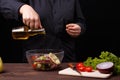 Chef pouring oil on greek salad, cooking process, restaurant con Royalty Free Stock Photo