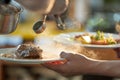 Chef pouring sauce over steak. Close up of cooking at garden party. Two plates in hand, with steak and salmon, in coloured Royalty Free Stock Photo