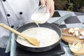 Chef pouring whipping cream in the pan for cooking mushroom cream soup