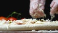 Chef pours cheese on pizza. Frame. Professional chef of Italian cuisine in gloves pours grated cheese on raw pizza
