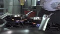 Chef pours fresh oil onto frying pans on contemporary stove