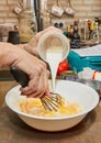 Chef pours milk from measuring cup into whisked eggs Royalty Free Stock Photo