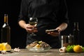 Chef pours, tastes Italian dry wine with oysters with lemon on a black background, the concept of seafood, wine, menus, recipes,