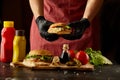 The chef prepares a burger, a hamburger on a background with ingredients. Delicious and fast food. A menu, a cafe, fast food, cate