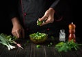 The chef prepares food from fresh vegetables in the kitchen. Lettuce salad prepared by the chef hands. Vegetarian cuisine Royalty Free Stock Photo