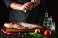 The chef prepares fresh fish bighead carp sprinkling pepper. Preparing to cook fish food. Working environment in restaurant or