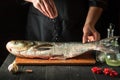 The chef prepares fresh fish bighead carp sprinkling salt. Preparing to cook fish food. Working environment in the restaurant